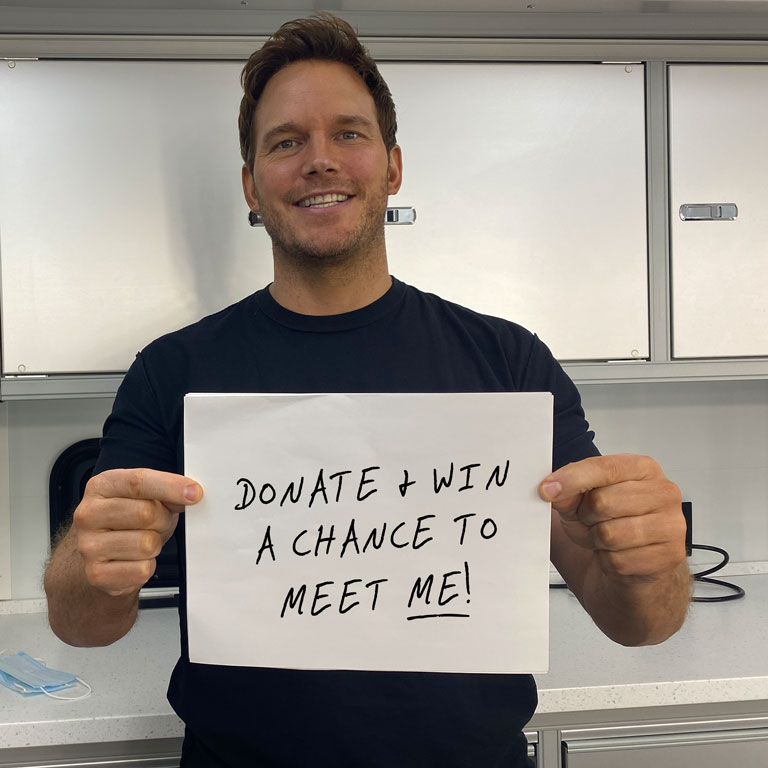 Chris Pratt holding sign saying Donate and Win a Chance to Meet Me