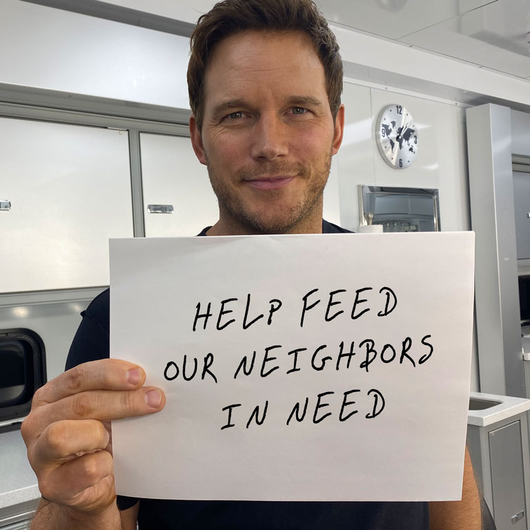 Chris Pratt holding sign saying Help Our Neighbors In Need